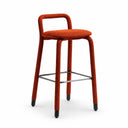 A modern bar stool with a textured rust-orange woven seat and backrest, supported by four slim metal legs with black feet and a central footrest bar, set against a clean white studio background.