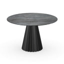 A modern round dining table with a dark gray wood-grain top and a sculptural pleated pedestal base in black, shown on a plain white background.
