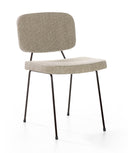 A modern dining chair with a textured light beige fabric upholstered seat and backrest, supported by slim black metal legs, shown against a plain white background.