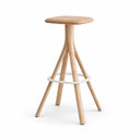 A minimalist wooden stool with a round natural oak seat, three angled legs, and a thin white circular footrest ring, shown against a solid light gray background.