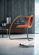 Timeless cantilever lounge chair by Luxy with rust upholstery and bronze-toned continuous steel frame in a contemporary office