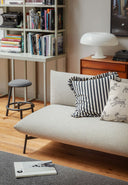 Close-up of the Midj Area DV2 M TS upholstered sofa in a contemporary bookshelf-lined living room
