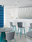 Gray polypropylene Midj Calla M PP armless counter stools with turquoise metal legs at a bright cafe bar