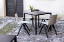 Black Midj Fold square metal dining table and white side chairs in a stone-paved courtyard