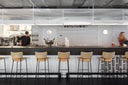 Midj Master M LG wood-veneer bar stools with slim black metal frames along a contemporary restaurant counter
