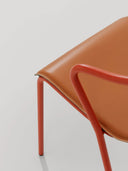Close-up of orange hide leather upholstery and curved metal arm on Midj Ola P M CU armchair