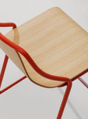 Close-up of Midj Ola P M LG armchair showing curved ashwood seat and contrasting red tubular steel arm frame