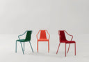 Three Midj Ola P M TS upholstered dining armchairs in green, orange and burgundy finishes on a neutral background