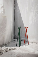 Midj Pippi coat racks in green and red metal displayed against a sculptural plaster wall