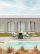 Midj Plissé 59-inch round outdoor dining table with dark green pleated pedestal base alongside a swimming pool