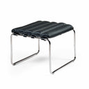 A modern black leather ottoman stool with a wavy, channel-tufted seat and a chrome steel frame, shown on a clean white background.