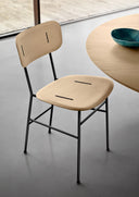 Midj Piuma S M LG dining chair with pale wood seat and back and black metal legs beside a modern table