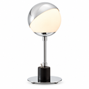 A modern table lamp with a spherical shade made of polished silver metal and a warm white frosted glass half, mounted on a chrome stem with a black cylindrical base and a round silver footplate.