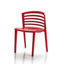 A bright red plastic dining chair with a curved backrest and slatted design, shown from a three-quarter angle on a white background with a soft reflection.