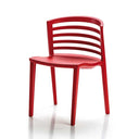 A bright red plastic dining chair with a curved backrest and slatted design, shown from a three-quarter angle on a white background with a soft reflection.